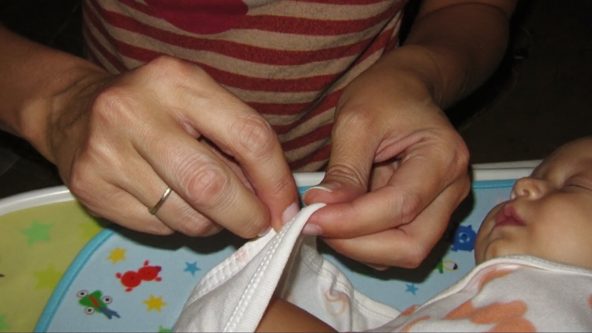 Hände kämpfen mit Onesie-Buttons